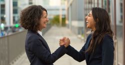 female coworkers celebrating outside an office building 